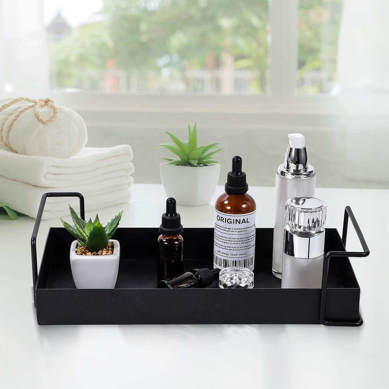 Black metal bathroom vanity tray with essential oils and decor items on a white countertop.