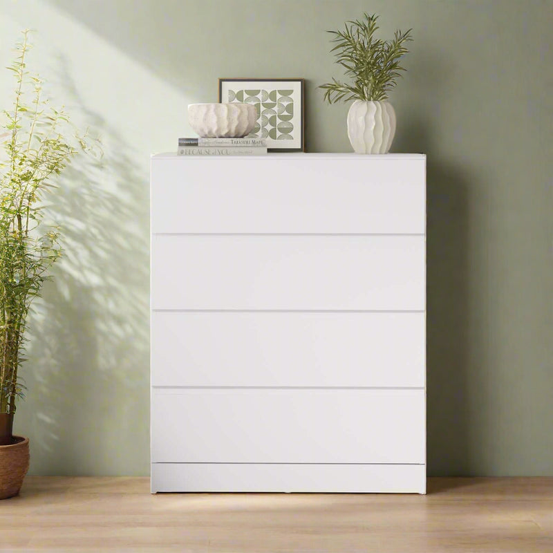 Modern 4 drawer dresser in a bedroom setting with decorative items on top.
