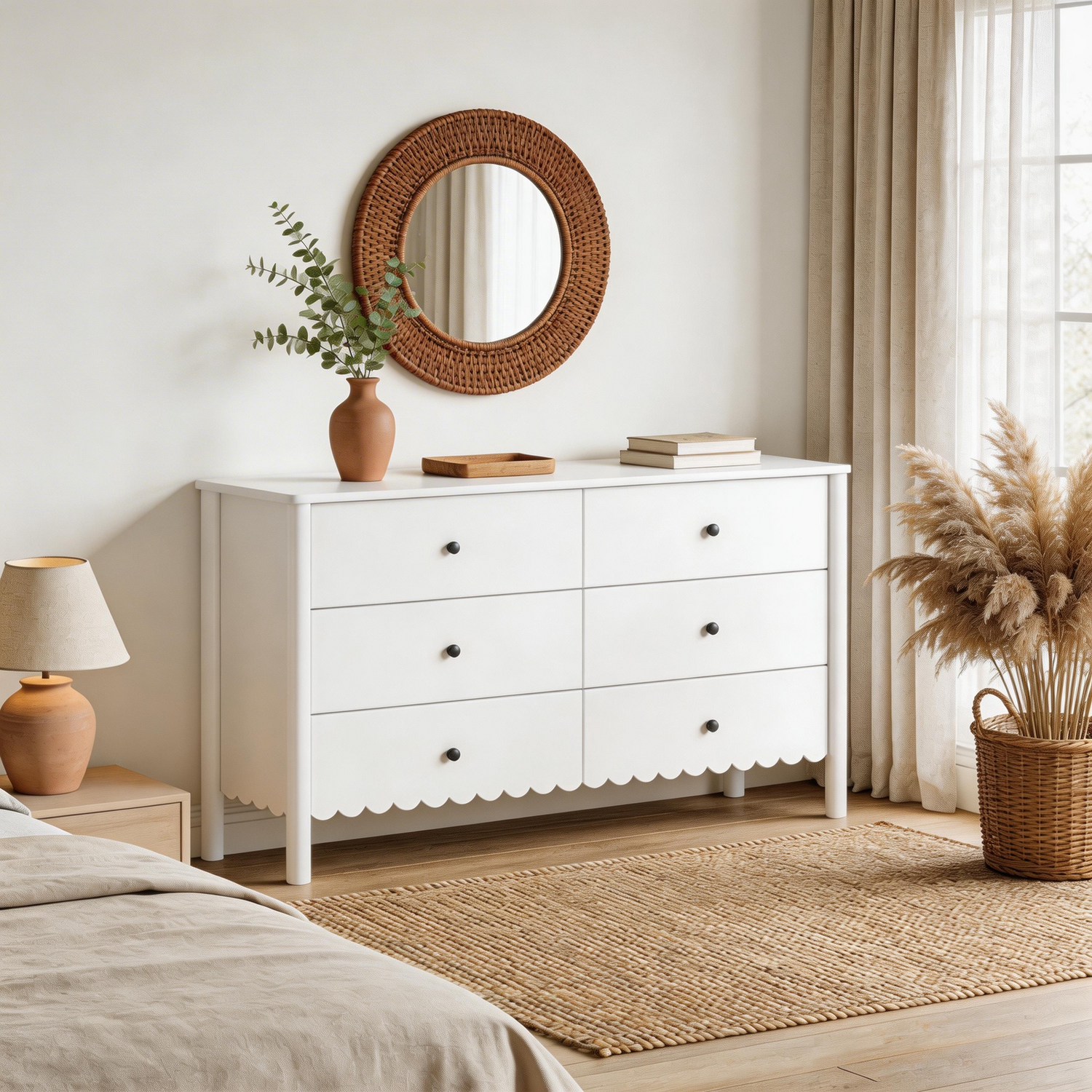White dresser with scalloped edge in a bedroom setting with a round mirror, lamp, and plants.