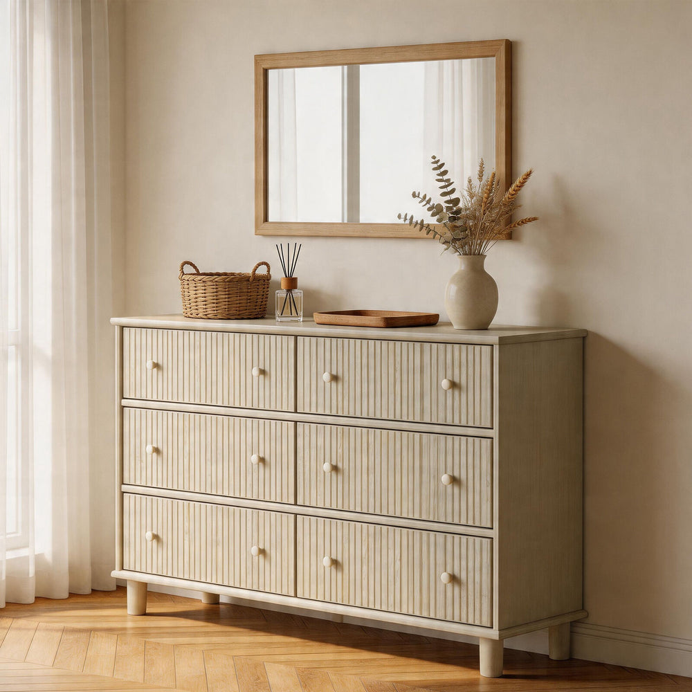 Beige dresser with decorative items in a room with a mirror and curtains.