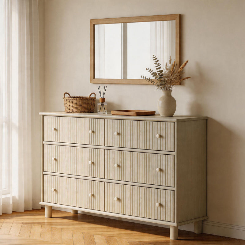 Beige dresser with decorative items in a room with a mirror and curtains.