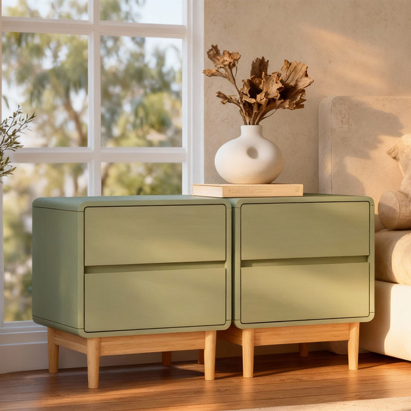 Green sideboard with wooden legs in a room with a window and decorative vase.