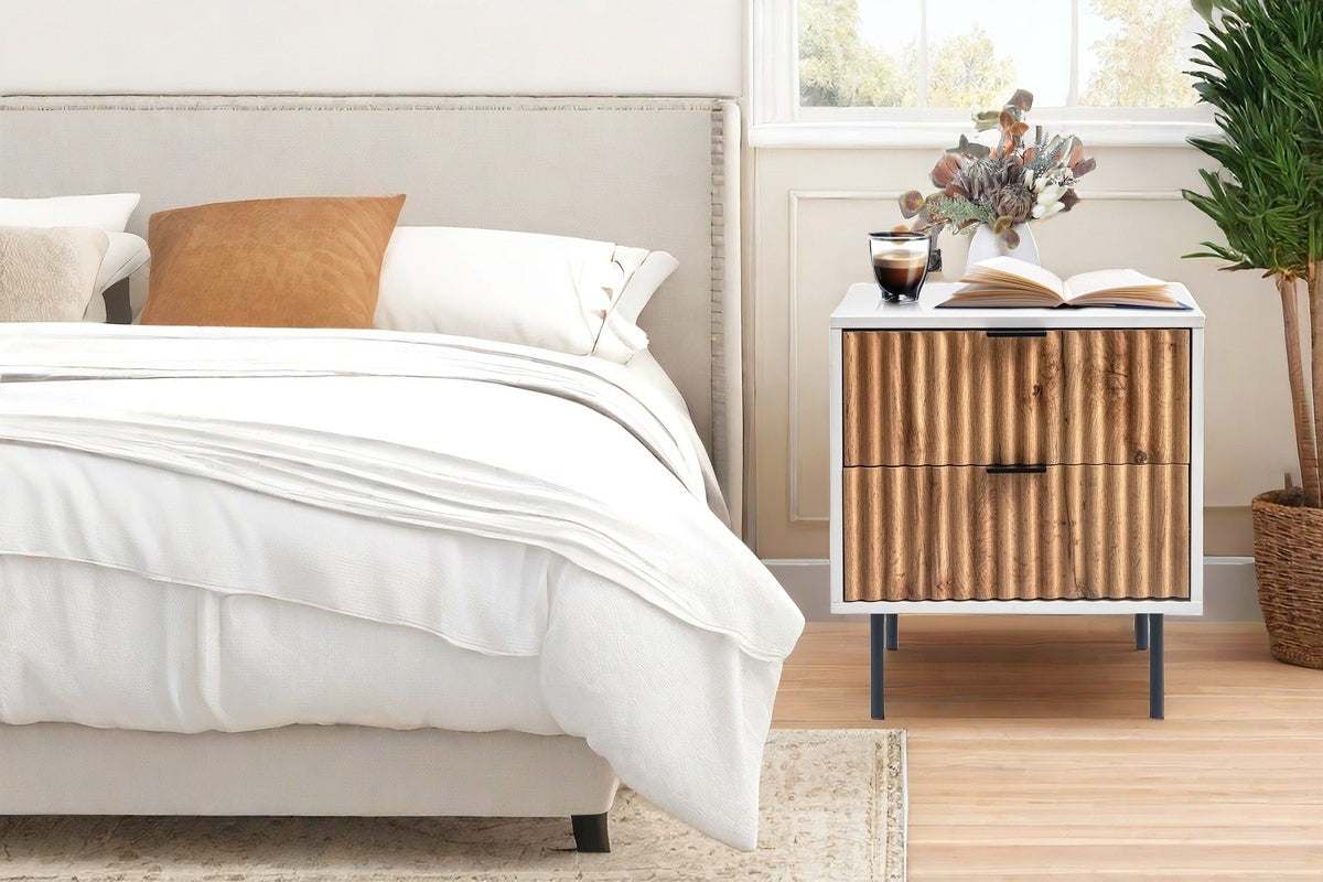 Chelsea 2-Drawer Bedside Table with white and timber wavy facade, placed beside a bed in a stylish bedroom setting.