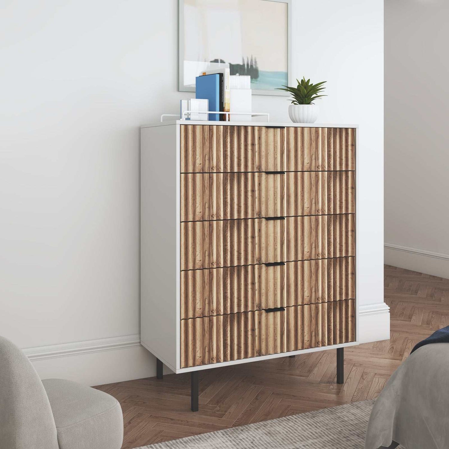 Chelsea 5-Drawer Chest of Drawers with white and timber wavy front, black handles, and metal legs in a bedroom setting.