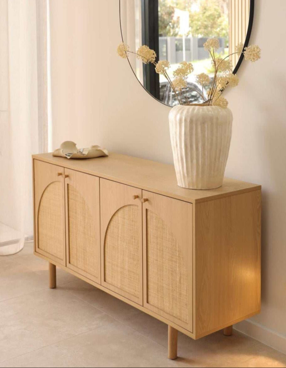 Wooden sideboard with a vase of flowers and decorative items in a room.